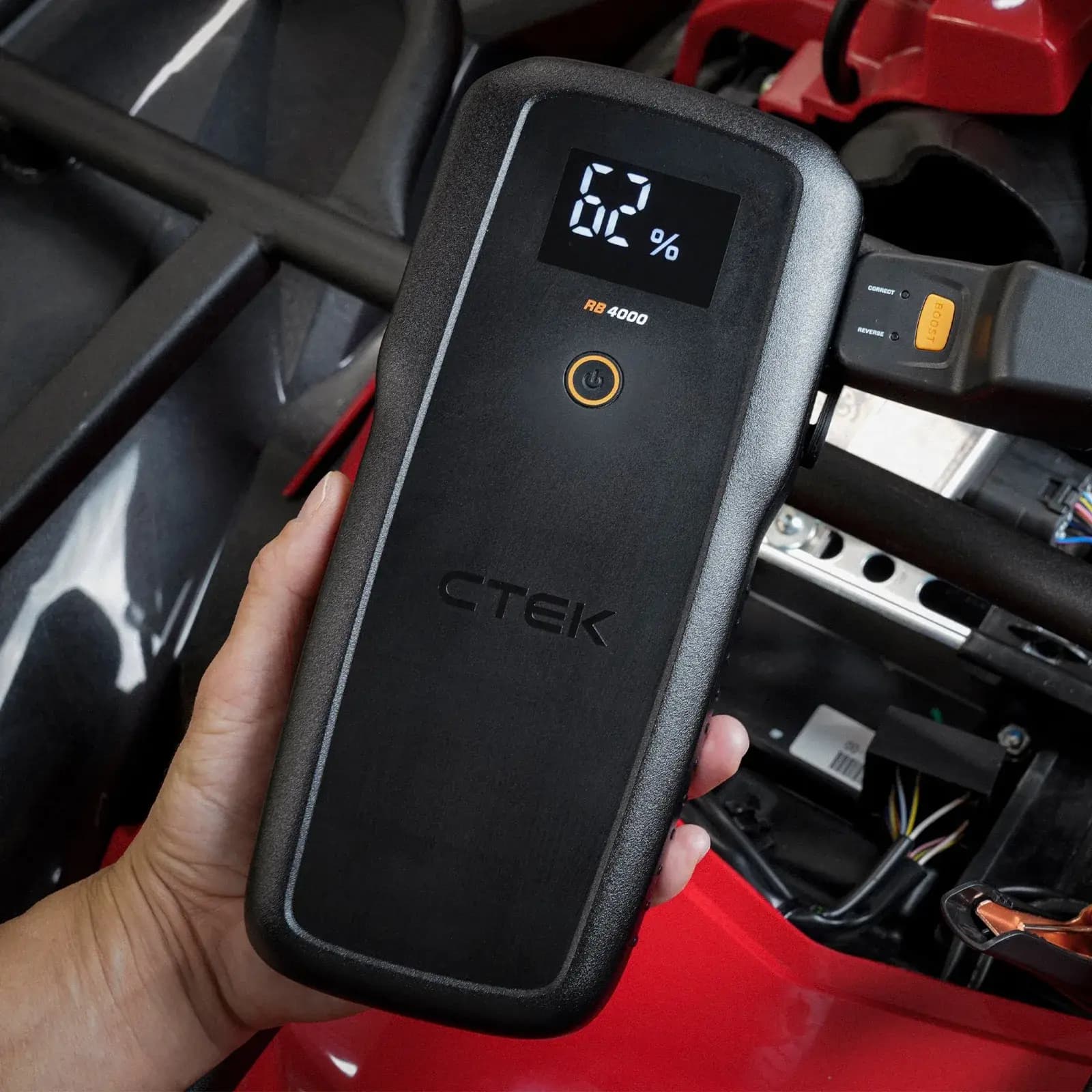 Hand holding the RB 4000 next to a vehicle battery